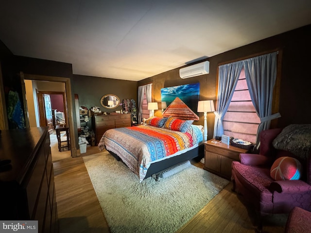 bedroom with hardwood / wood-style floors and a wall unit AC