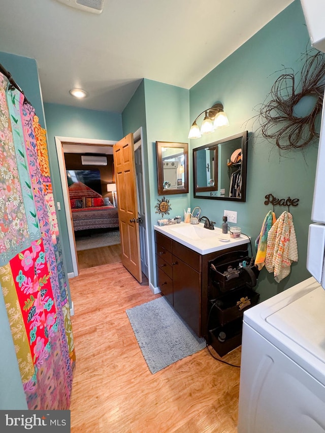 bathroom with wood-type flooring, vanity, and washer / dryer