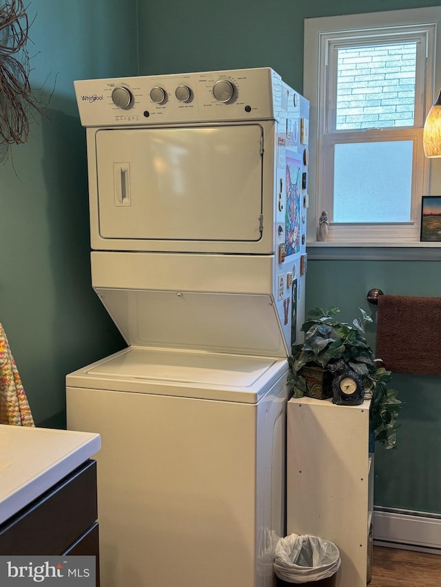 laundry room featuring wood-type flooring, baseboard heating, and stacked washer and dryer