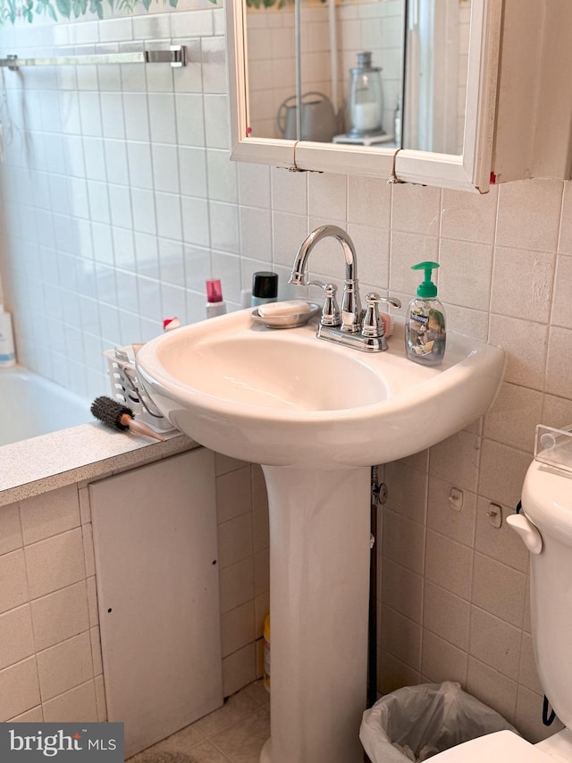 bathroom with toilet, tile walls, and tasteful backsplash