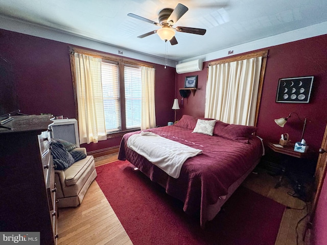 bedroom featuring an AC wall unit, ceiling fan, and wood-type flooring