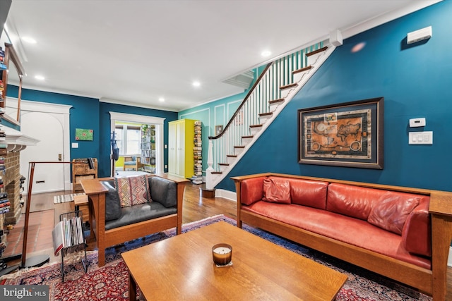 living room with hardwood / wood-style flooring, ornamental molding, and a fireplace