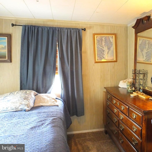 bedroom featuring wooden walls and dark carpet