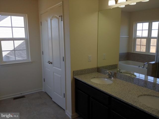 bathroom with a washtub, vanity, and tile patterned flooring