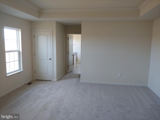 unfurnished room with light carpet, a raised ceiling, and ornamental molding