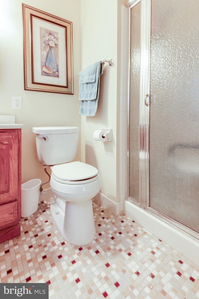 bathroom featuring vanity, toilet, and a shower with door