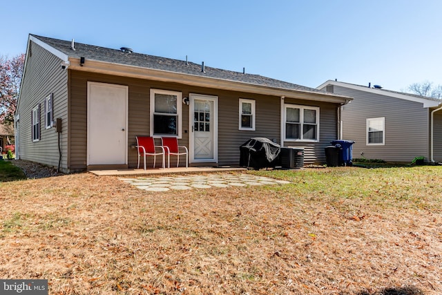 back of house with cooling unit and a lawn