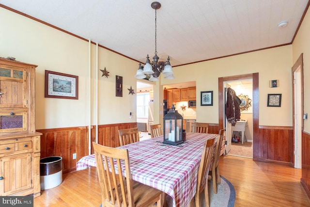 dining area with a notable chandelier, light wood-type flooring, and crown molding