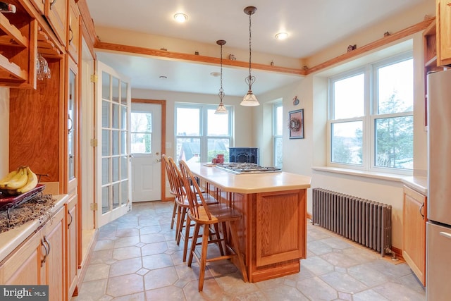 kitchen with a breakfast bar, a center island, radiator, appliances with stainless steel finishes, and decorative light fixtures