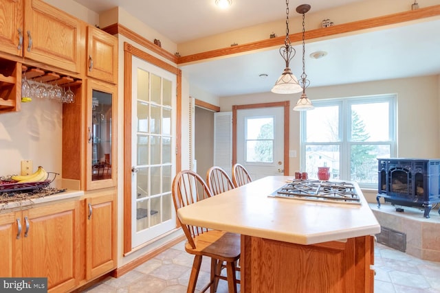 kitchen with a kitchen breakfast bar, a wealth of natural light, pendant lighting, and stainless steel gas cooktop