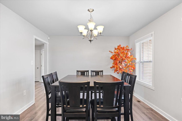 dining space with wood-type flooring and a notable chandelier