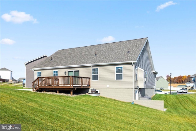 rear view of property featuring a wooden deck and a lawn