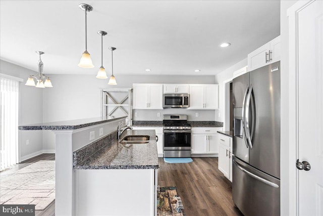 kitchen with a breakfast bar, sink, hanging light fixtures, appliances with stainless steel finishes, and white cabinets