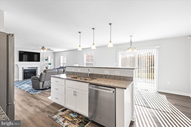 kitchen featuring sink, white cabinetry, dark stone counters, pendant lighting, and stainless steel appliances