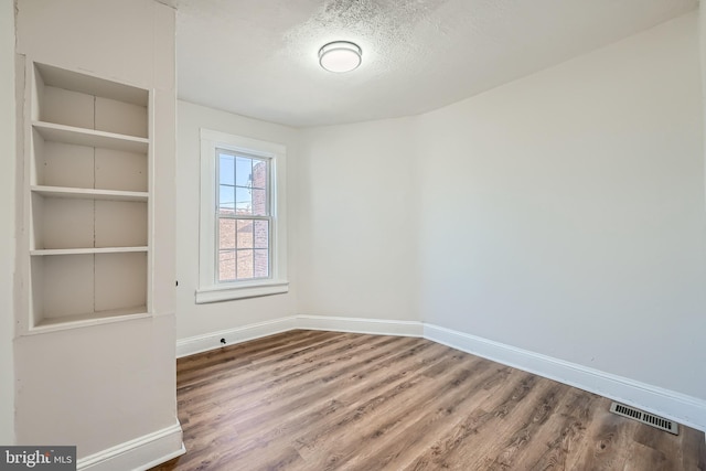 spare room with hardwood / wood-style floors and a textured ceiling