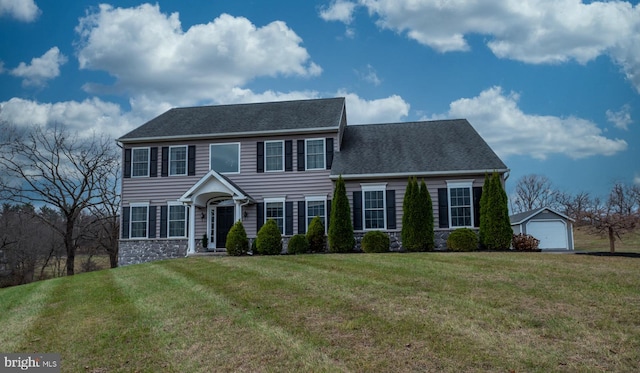 colonial inspired home with an outbuilding, a garage, and a front lawn