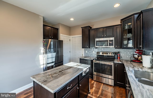 kitchen featuring dark hardwood / wood-style flooring, stainless steel appliances, light stone counters, and tasteful backsplash