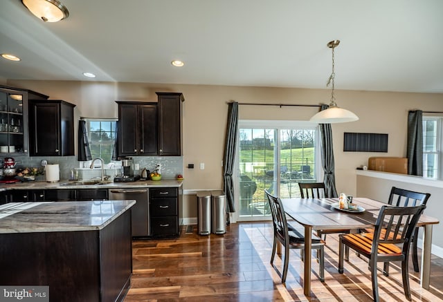 kitchen featuring backsplash, stainless steel dishwasher, dark wood-type flooring, sink, and hanging light fixtures