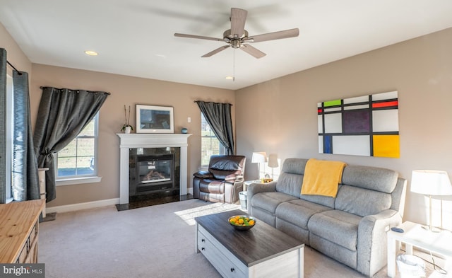 living room featuring a high end fireplace, light carpet, and ceiling fan