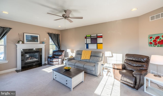 living room with ceiling fan, light colored carpet, and a fireplace