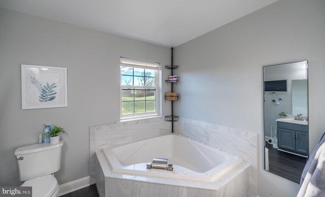 bathroom featuring hardwood / wood-style floors, vanity, a relaxing tiled tub, and toilet