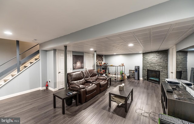 living room featuring a stone fireplace and dark hardwood / wood-style floors