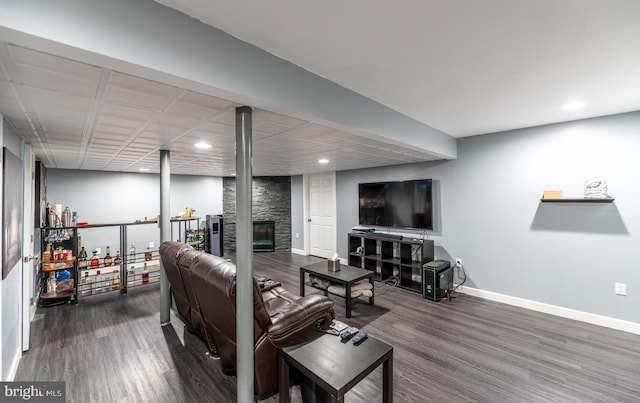 living room featuring dark hardwood / wood-style flooring and a stone fireplace