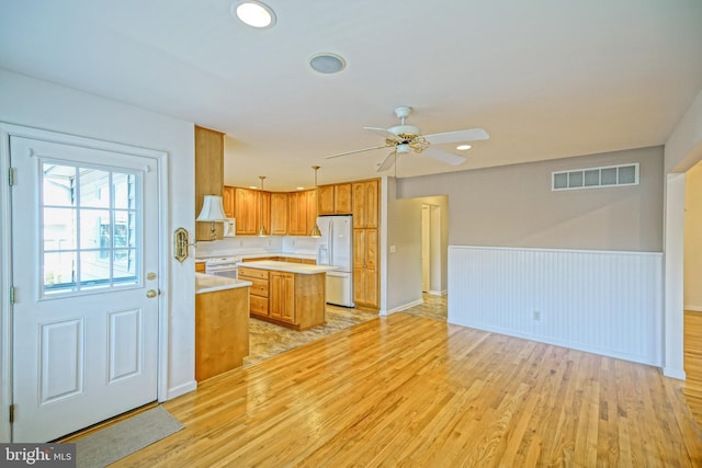 kitchen featuring ceiling fan, a center island, pendant lighting, white appliances, and light wood-type flooring