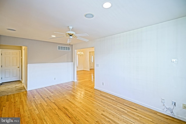 spare room with light hardwood / wood-style floors and ceiling fan with notable chandelier