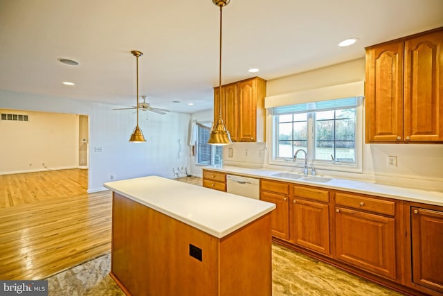 kitchen featuring white dishwasher, sink, pendant lighting, light hardwood / wood-style flooring, and a kitchen island