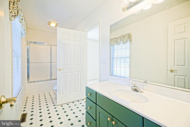 full bathroom featuring vanity, toilet, and bath / shower combo with glass door