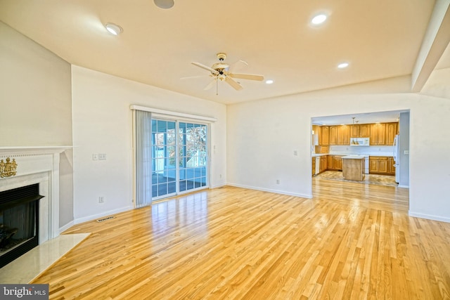 unfurnished living room with a fireplace, ceiling fan, and light hardwood / wood-style flooring