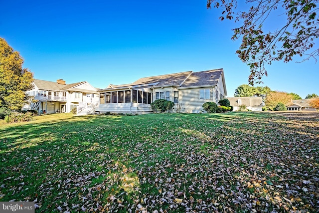 back of property featuring a lawn and a sunroom