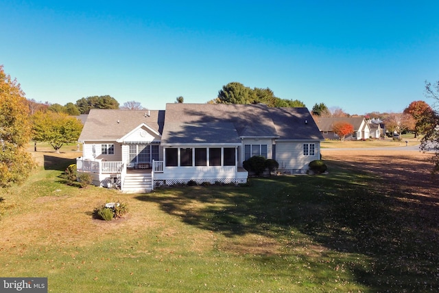 rear view of house featuring a sunroom and a yard