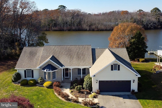 view of front of home with a garage, a water view, and a front lawn