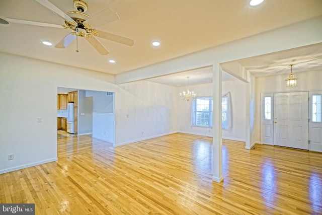 interior space with ceiling fan with notable chandelier and light wood-type flooring