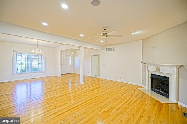 unfurnished living room with hardwood / wood-style flooring and ceiling fan with notable chandelier