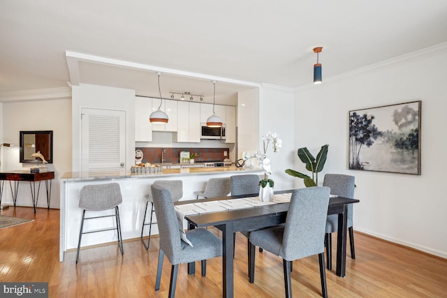 dining area with light wood-type flooring and crown molding