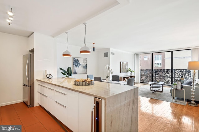 kitchen with light stone counters, stainless steel fridge, wine cooler, pendant lighting, and white cabinets