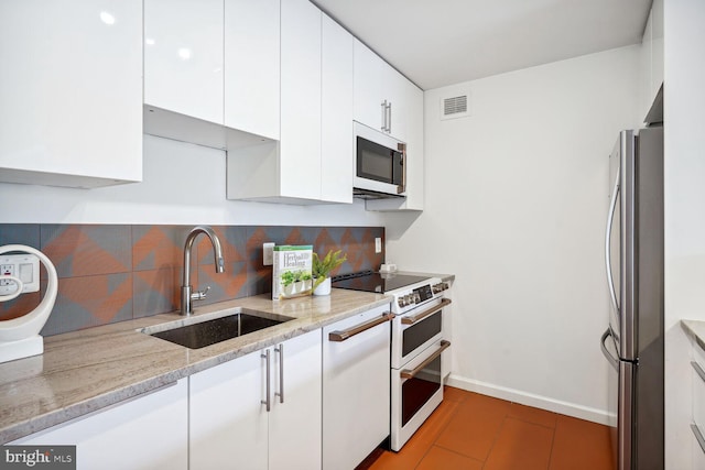 kitchen with stainless steel appliances, white cabinets, sink, tasteful backsplash, and light stone countertops