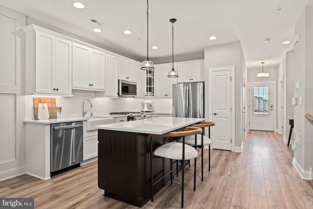 kitchen featuring a kitchen island, light wood-type flooring, white cabinets, and stainless steel appliances