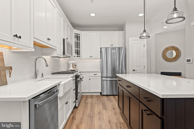 kitchen with stainless steel appliances, light hardwood / wood-style floors, hanging light fixtures, and white cabinets