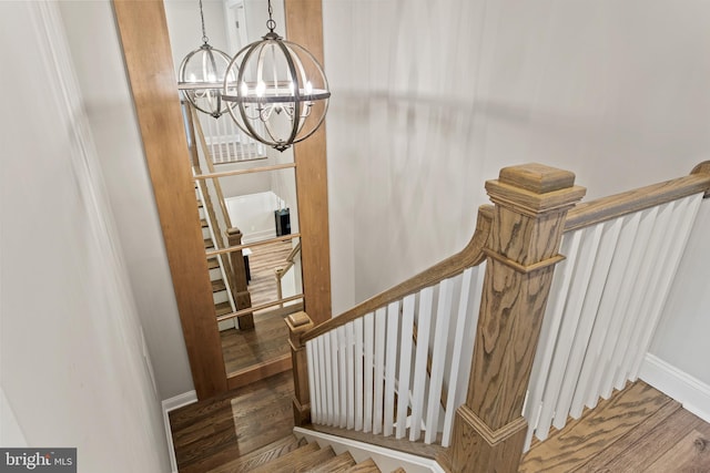 staircase featuring an inviting chandelier and hardwood / wood-style floors