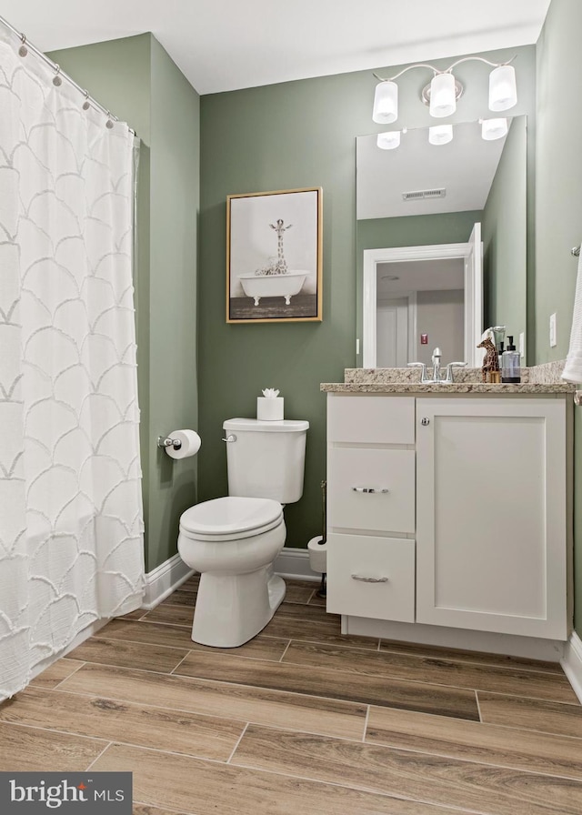 bathroom featuring wood-type flooring, toilet, and vanity