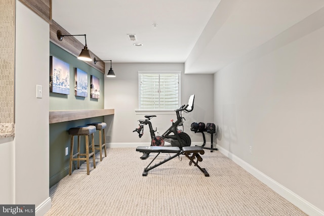 workout room featuring bar area and light carpet