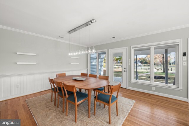 dining area with light hardwood / wood-style floors and ornamental molding