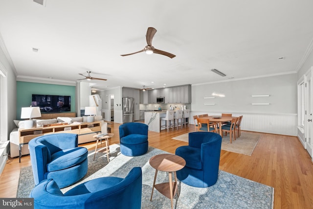 living room featuring ceiling fan, light hardwood / wood-style floors, and ornamental molding