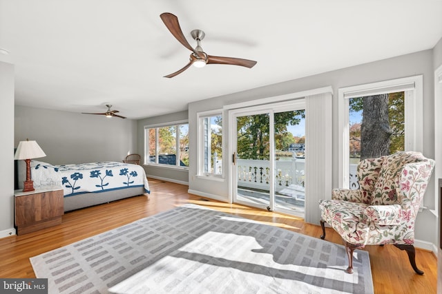 bedroom featuring access to outside, multiple windows, ceiling fan, and hardwood / wood-style floors