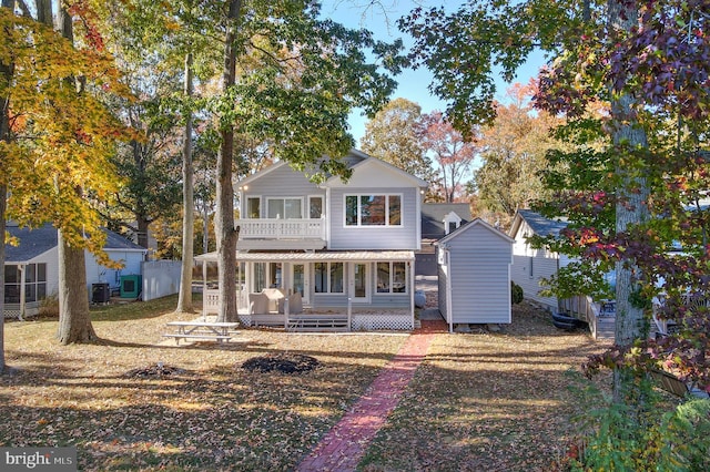 back of property with a lawn, central air condition unit, a porch, a balcony, and a shed