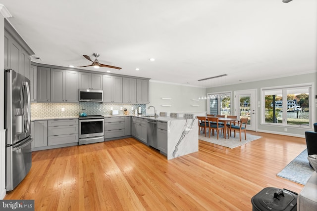 kitchen with gray cabinetry, light wood-type flooring, and appliances with stainless steel finishes